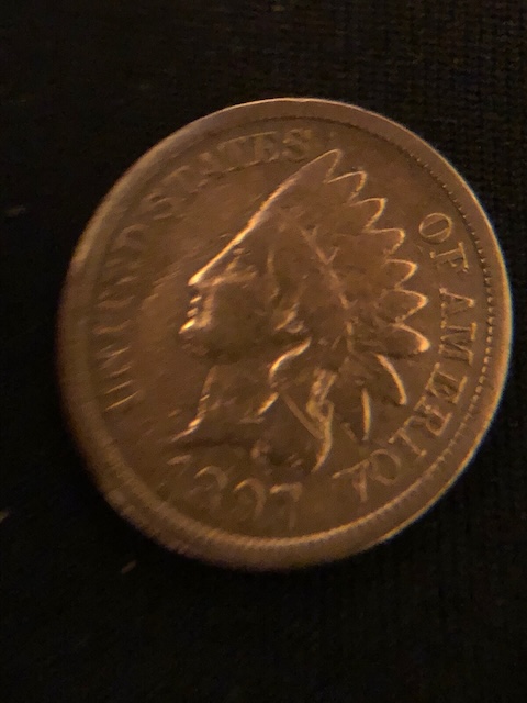 1897 Indian Head Penny die cud error showing raised blob of metal at rim caused by a broken die section
